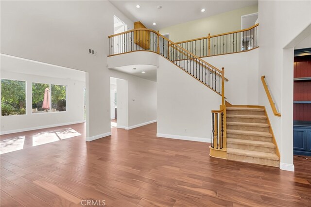 unfurnished living room with a towering ceiling and hardwood / wood-style flooring