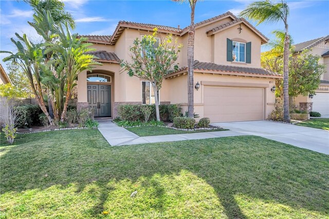 mediterranean / spanish home with a garage and a front lawn