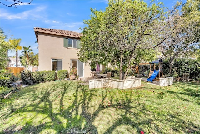 rear view of property with a playground, a yard, and a patio