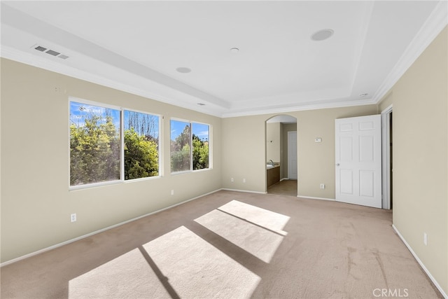 unfurnished bedroom featuring connected bathroom, crown molding, light colored carpet, and a raised ceiling