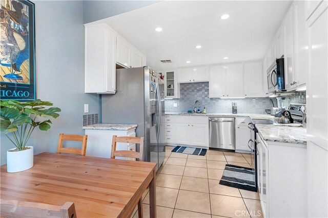 kitchen with backsplash, sink, light tile patterned floors, appliances with stainless steel finishes, and white cabinetry