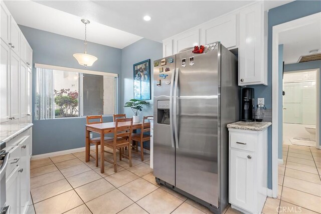 kitchen with stainless steel refrigerator with ice dispenser, hanging light fixtures, light stone countertops, light tile patterned flooring, and white cabinetry