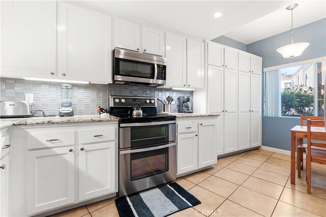 kitchen featuring backsplash, white cabinetry, stainless steel appliances, and hanging light fixtures