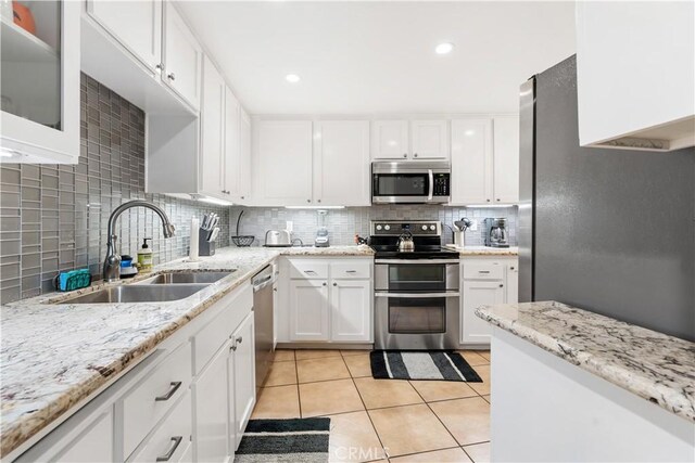 kitchen with sink, light tile patterned floors, tasteful backsplash, white cabinets, and appliances with stainless steel finishes