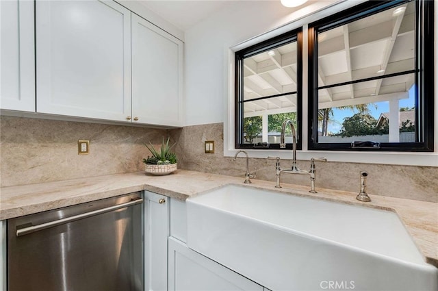 kitchen with light stone countertops, white cabinetry, sink, tasteful backsplash, and stainless steel dishwasher