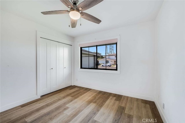 unfurnished bedroom featuring ceiling fan, light wood-type flooring, and a closet