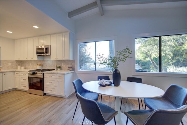 kitchen with vaulted ceiling with beams, white cabinetry, a healthy amount of sunlight, and appliances with stainless steel finishes