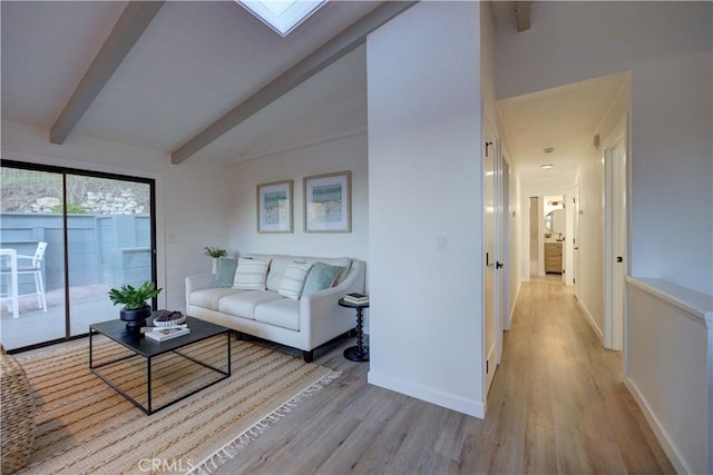 living room featuring vaulted ceiling with skylight and light wood-type flooring