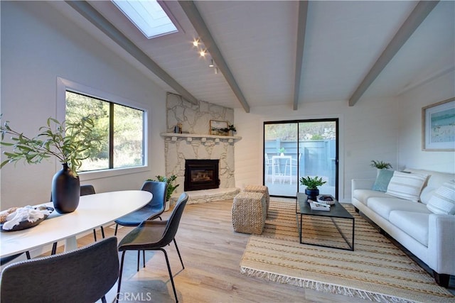 living room featuring vaulted ceiling with skylight, light hardwood / wood-style floors, and a fireplace