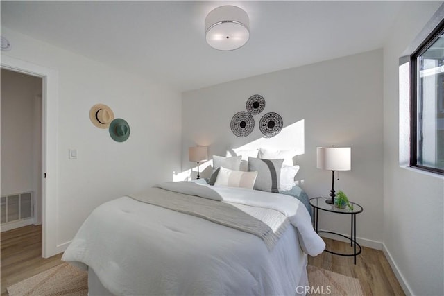 bedroom featuring wood finished floors, visible vents, and baseboards