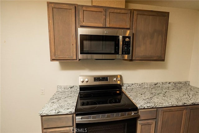 kitchen with light stone countertops and appliances with stainless steel finishes