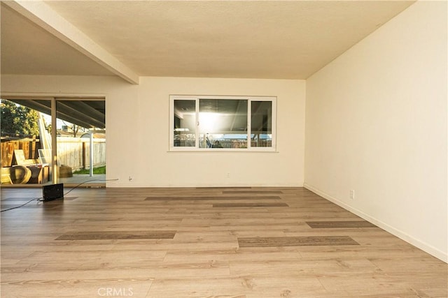 unfurnished room with beam ceiling and light hardwood / wood-style floors