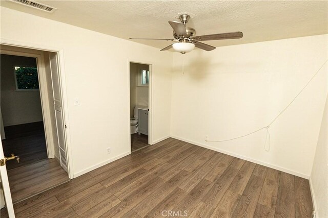 unfurnished bedroom featuring ensuite bathroom, dark hardwood / wood-style floors, a textured ceiling, and ceiling fan