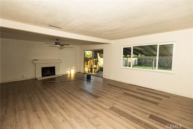 unfurnished living room featuring hardwood / wood-style floors, a brick fireplace, and a wealth of natural light