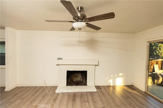 unfurnished living room with ceiling fan, hardwood / wood-style floors, a textured ceiling, and a fireplace