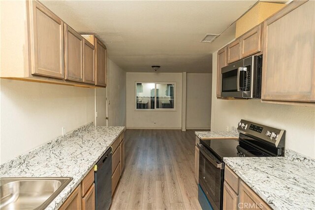 kitchen featuring appliances with stainless steel finishes, light stone countertops, and light hardwood / wood-style floors