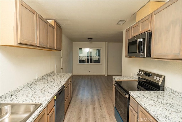 kitchen with stainless steel appliances, light stone countertops, and light wood-type flooring