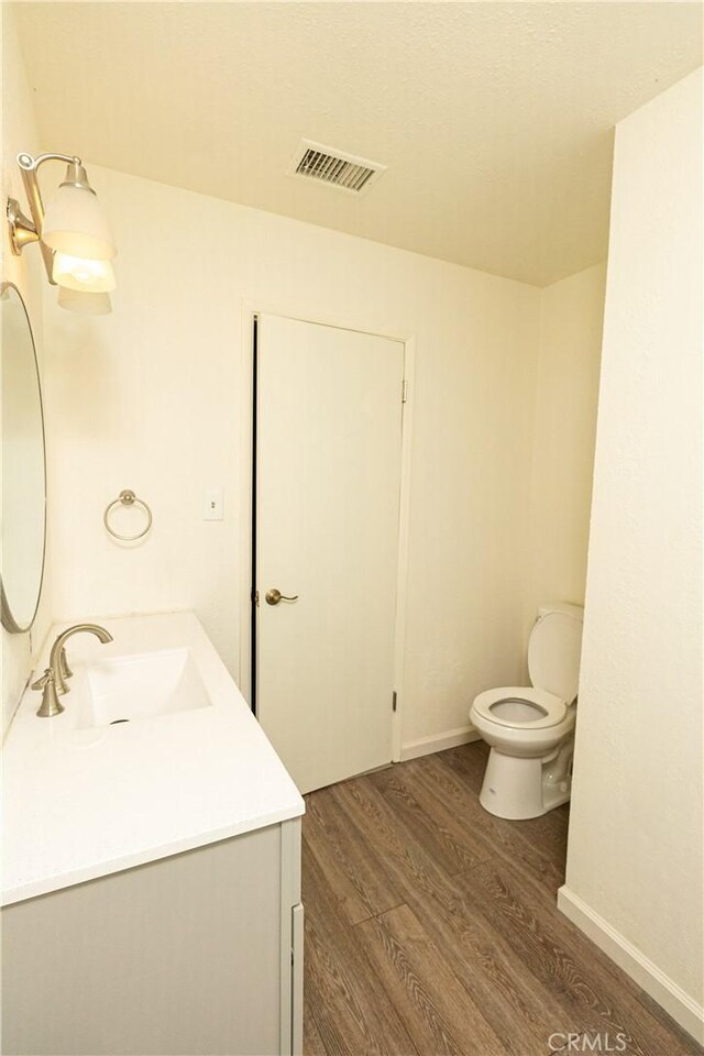 bathroom with wood-type flooring, vanity, and toilet