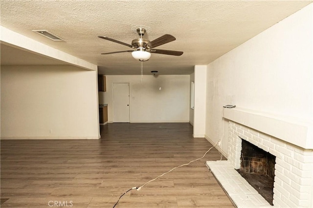 unfurnished living room featuring a fireplace, wood-type flooring, a textured ceiling, and ceiling fan