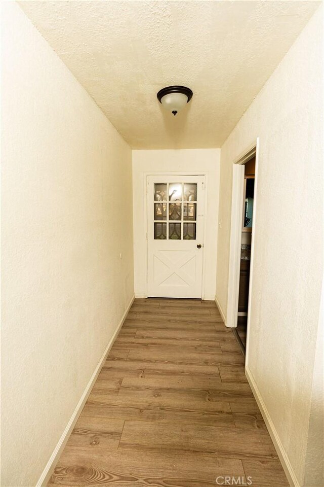 hallway with hardwood / wood-style floors and a textured ceiling