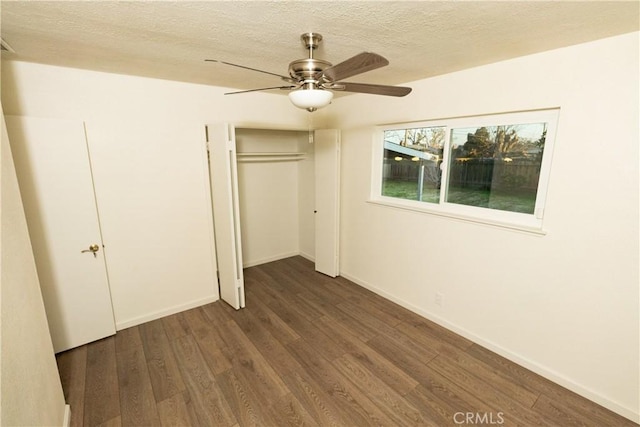 unfurnished bedroom featuring dark wood-type flooring, ceiling fan, a closet, and a textured ceiling