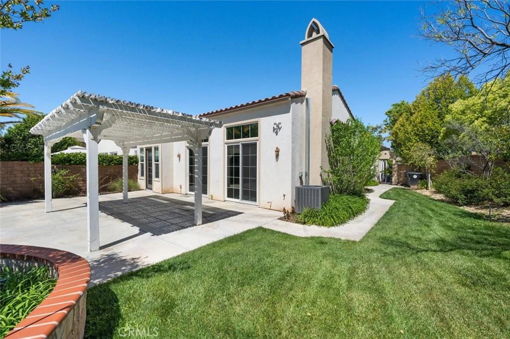 back of house featuring a pergola, a yard, cooling unit, and a patio