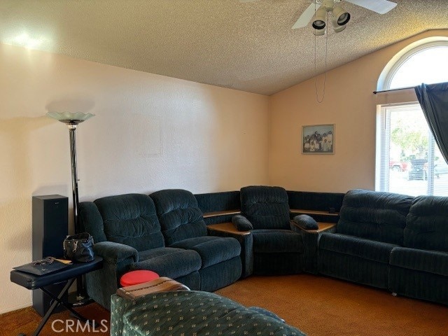 living room featuring ceiling fan, carpet floors, a textured ceiling, and vaulted ceiling