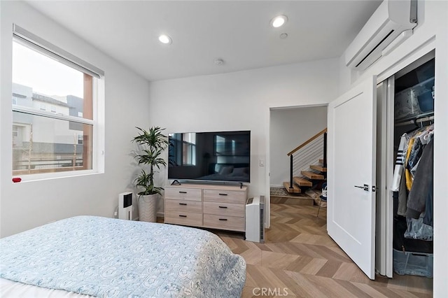 bedroom with a wall mounted air conditioner, light parquet floors, and a closet