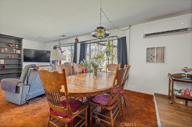 dining room featuring a textured ceiling, dark hardwood / wood-style floors, and a wall unit AC