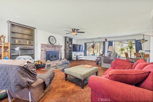 living room featuring ceiling fan, a wood stove, and carpet floors