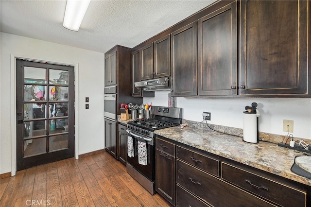 kitchen featuring dark hardwood / wood-style floors, light stone countertops, a textured ceiling, stainless steel appliances, and dark brown cabinets