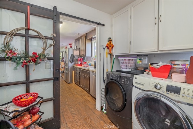 clothes washing area with cabinets, hardwood / wood-style floors, sink, and washing machine and clothes dryer