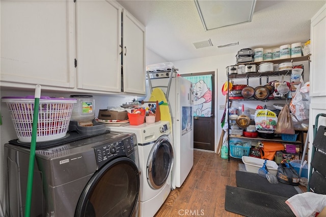 laundry area featuring cabinets, a textured ceiling, dark hardwood / wood-style floors, and washing machine and dryer