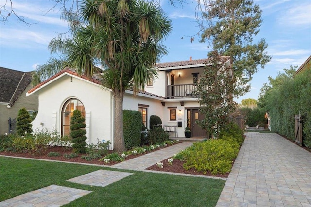 mediterranean / spanish-style home with a balcony and a front lawn