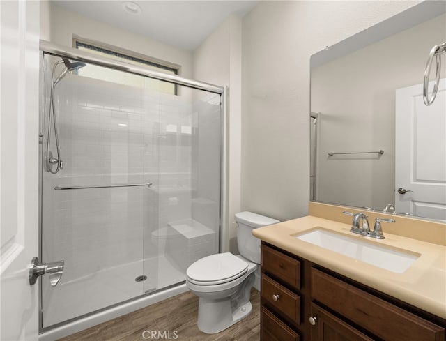 bathroom featuring hardwood / wood-style floors, vanity, toilet, and a shower with shower door