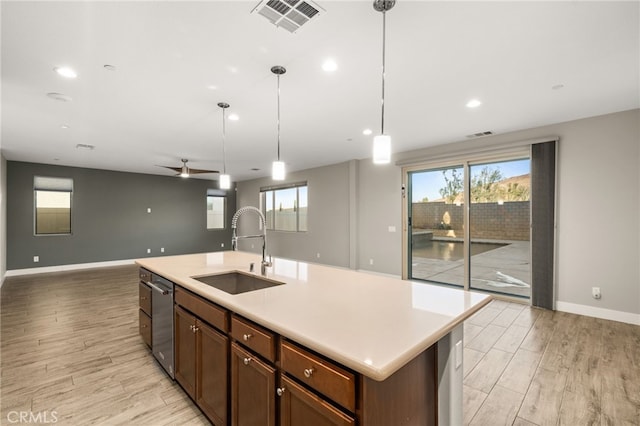 kitchen with ceiling fan, sink, stainless steel dishwasher, decorative light fixtures, and a kitchen island with sink