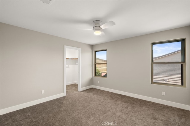 unfurnished bedroom with carpet floors, a closet, a spacious closet, and ceiling fan