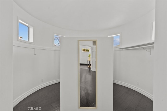 basement featuring dark wood-type flooring, a wealth of natural light, and baseboards