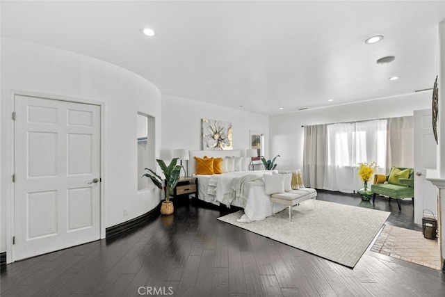 bedroom with dark wood-style floors, arched walkways, and recessed lighting