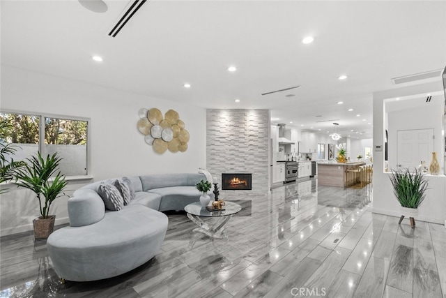 living room featuring baseboards, a fireplace, visible vents, and recessed lighting