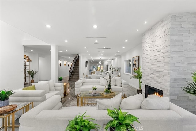 living room with recessed lighting, stairway, and a stone fireplace