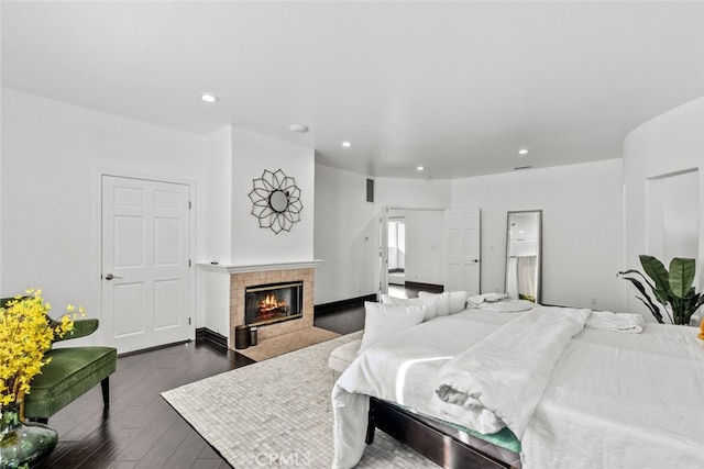 bedroom with dark wood-type flooring, recessed lighting, and a tiled fireplace