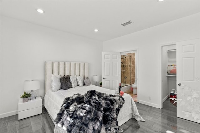 bedroom with a walk in closet, ensuite bathroom, and dark hardwood / wood-style flooring