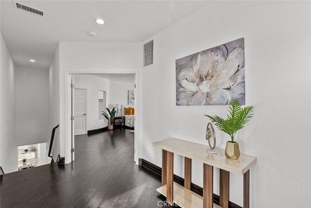 hallway featuring dark wood-type flooring, recessed lighting, visible vents, and baseboards