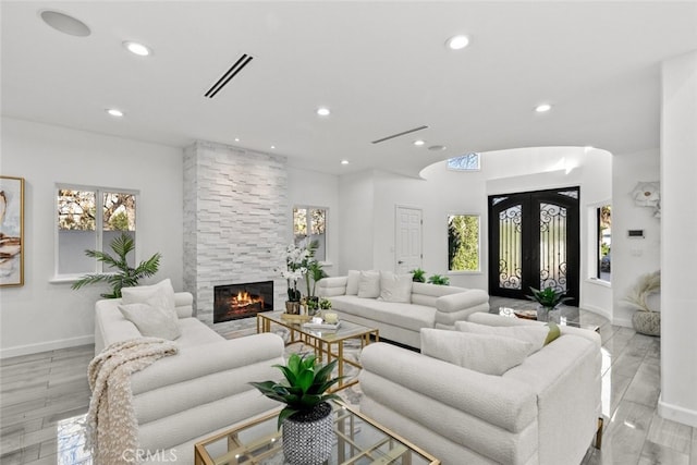 living room featuring french doors, recessed lighting, visible vents, light wood-style floors, and a stone fireplace