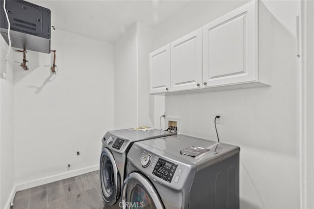 clothes washing area featuring washer and dryer, cabinet space, baseboards, and wood finished floors