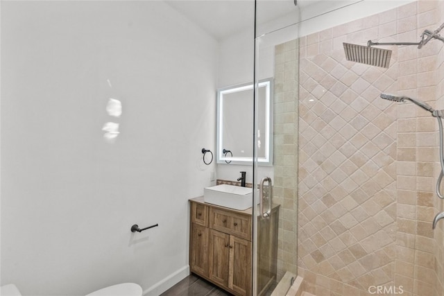 bathroom featuring toilet, a stall shower, baseboards, and vanity