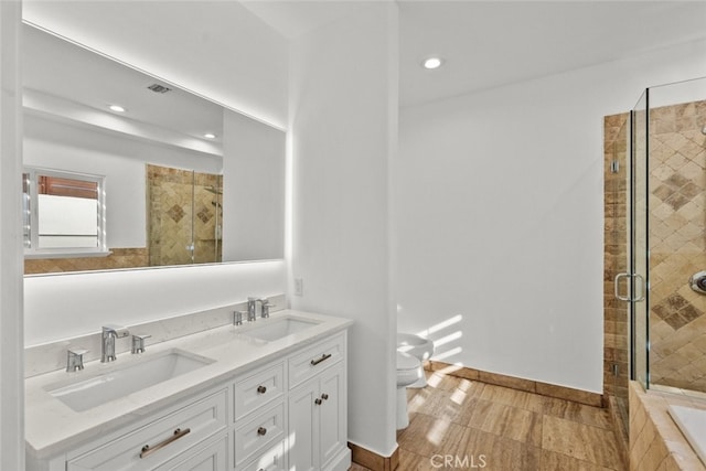 bathroom featuring double vanity, a shower stall, toilet, and a sink