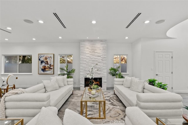 living room featuring baseboards, a fireplace, visible vents, and recessed lighting