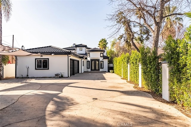 exterior space featuring driveway, an attached garage, a tile roof, and stucco siding